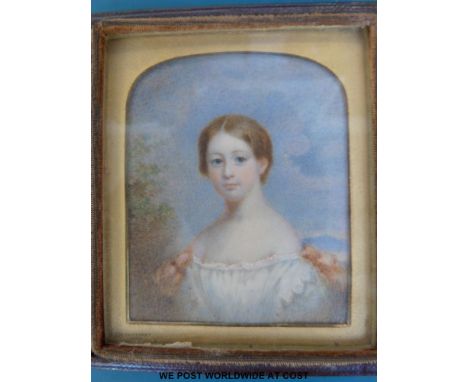 A 19th / 20thC portrait miniature of a young lady wearing an off the shoulder dress against a landscape, set in a folding lea