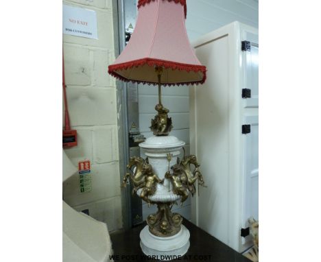 A ceramic lamp decorated with gilt metal cherubs and horses raised on a column in the form of a fish 