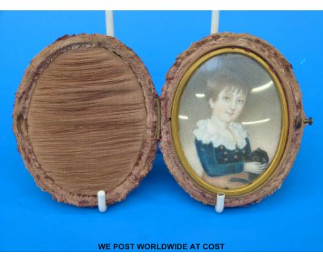 A Georgian oval portrait miniature of a young boy in a blue top with frilled neck, holding a black cat, in original velvet ca
