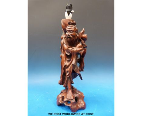 An oriental wooden lamp in the form of a bearded man holding a large nut