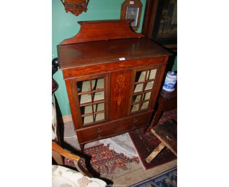 A possibly Edwardian Mahogany Cabinet having a pair of opposing glazed doors flanking a central panel with an urn, bows and g