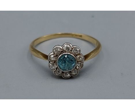 An 18ct gold ring with a central Aquamarine surrounded by Diamonds within a pierced setting, 2.2gms, ring size P
