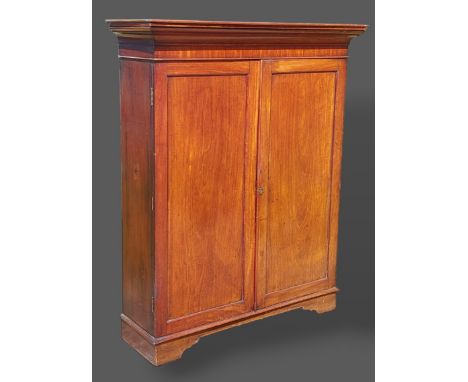 A Victorian mahogany bookcase, the moulded cornice above two panel doors enclosing shelves, raised upon bracket feet, 118cms 