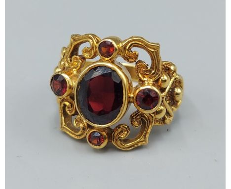 A 9ct gold ring set with central Garnet surrounded by four small Garnets within a pierced setting, 5.9gms, ring size O