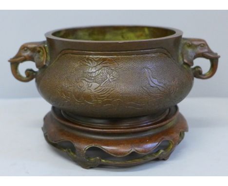 A 19th Century bronze censer on a wooden base, cast mark to base, 18cm wide including elephant handles 