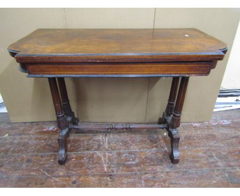A Victorian walnut and burr walnut foldover top card table, raised on a stretcher base, supported by four turned and fluted c