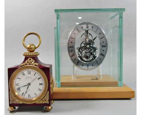 A contemporary chrome skeleton clock set within a plate glass and beechwood case and a further small decorative alarm clock w
