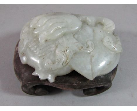 An old Chinese jade buckle with floral detail, raised on a carved wood stand 