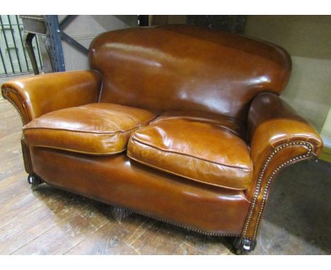 A traditional two seat leather sofa, with brass stud detail on fluted supports, 145cm wide 