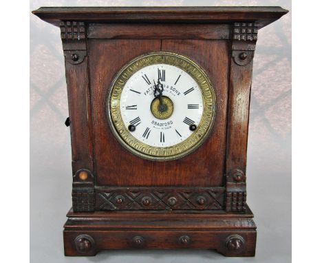 A late 19th century oak cased mantle clock, the eight day movement with alarm action and enamelled dial, the case with carved