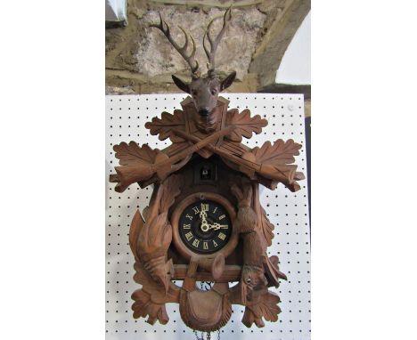 A Tyrolean cuckoo clock in the form of a chalet with applied detail showing hanging game, stag mount, hunting horn, etc 