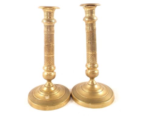 A pair of early 19th Century French seamed Brass candlesticks with engine milled decoration, wide circular bases and detachab