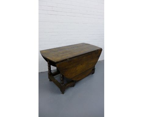 An early 19th century oak gate leg table with planked top, raised on turned supports and stretcher, on hoof feet 138 x 75cm 
