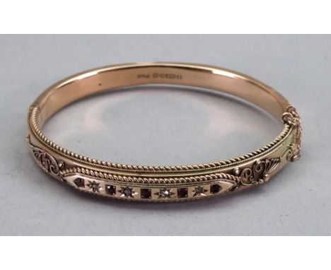 A 9ct gold, diamond and red gem oval hinged bangle, the front with four rose cut diamonds alternately star set between red ge