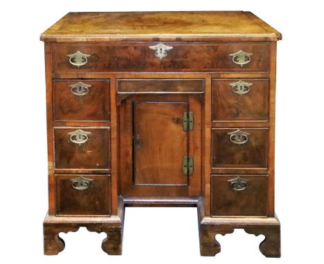 An early 18th century walnut feather and crossbanded kneehole desk, the moulded rectangular top with re-entrant corners above