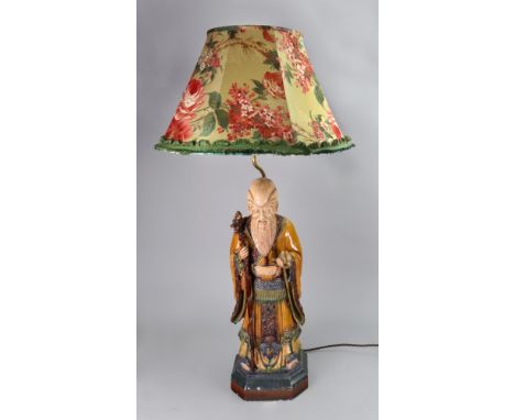 A Chinese pottery figure of Shoulao, late 19th/20th century, modelled standing in long robes holding a dragon headed staff an