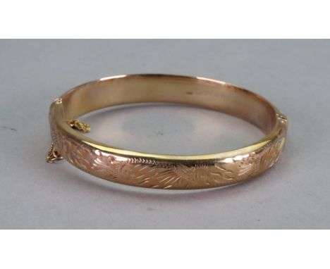 A 9ct gold hinged bangle, the front engraved with a scrolling foliate design, 13.26g gross, with a box. 