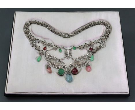 A silver, jade and multi-colour gemset necklace, the central silver panels with winged creature and filigree decoration mount