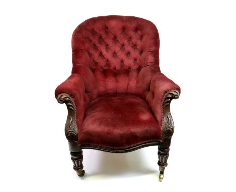 A Victorian walnut frame armchair, circa 1860, button down upholstered in claret velour, having foliate carved scroll arms, o