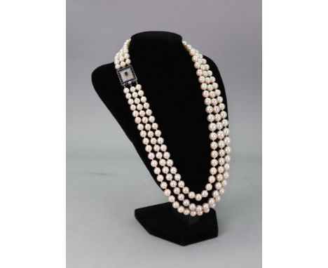 A triple-row necklace of graduated cultured pearls, on a square sapphire and diamond set clasp, the clasp centrally set with 