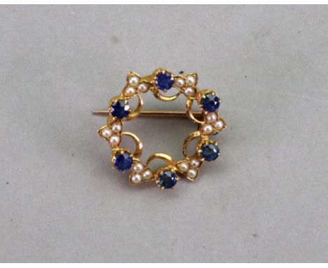 A gold, sapphire and seed pearl set wreath brooch, with six round sapphires between seed pearl trefoils and gold swags, stamp