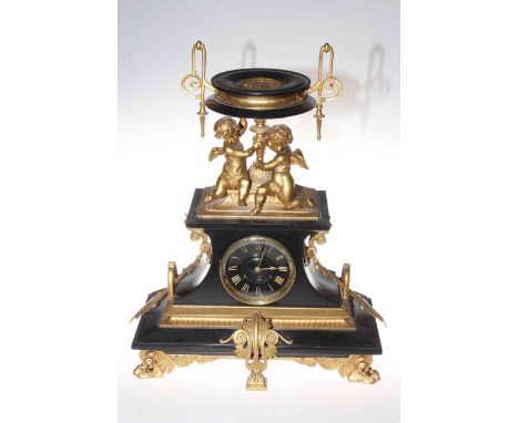 French 19th Century gilt metal mounted black marble clock, the extravagant shape with cherubs and urn above circular dial, wi