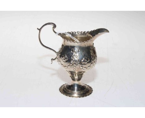 Silver helmet style cream jug embossed with swags and flower heads, marks worn.