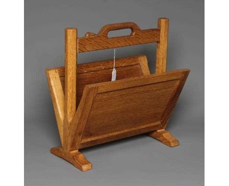 A ROBERT THOMPSON OAK MAGAZINE RACK with splayed panelled sides, central raised loop handle on turned faceted supports, the t