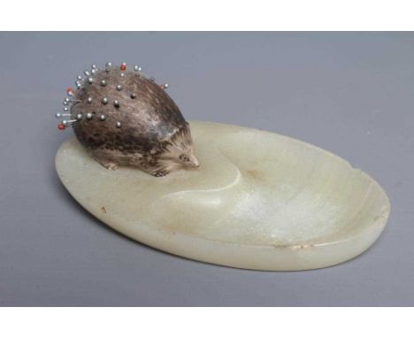 AN ASPREY NOVELTY PIN TRAY, the dished oval onyx base surmounted by an enamel hedgehog with 'pin holes', 2" long, base engrav