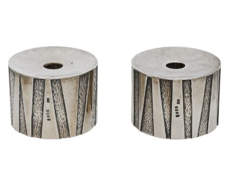A pair of silver tapersticks by Michael Kay, 1977, of squat cylindrical form, the sides with abstract polished and etched pan