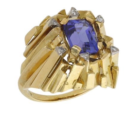 A tanzanite and diamond ring by Gilian Packard, 1972, the emerald-cut tanzanite in four-claw setting, within a bold architect