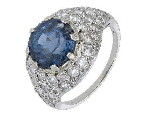 A sapphire and diamond bombé ring, set with a circular-cut sapphire in a surround of brilliant-cut diamonds, stamped ‘PLAT’, 