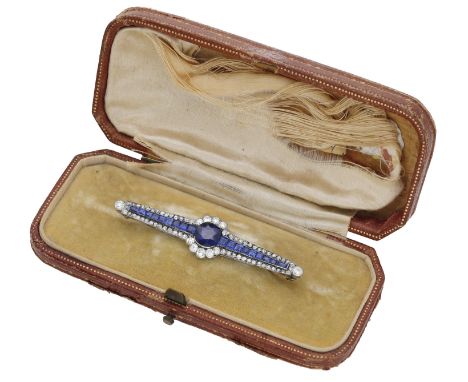 A sapphire and diamond bar brooch, circa 1920, the central circular-cut sapphire set between graduating calibré-cut sapphires