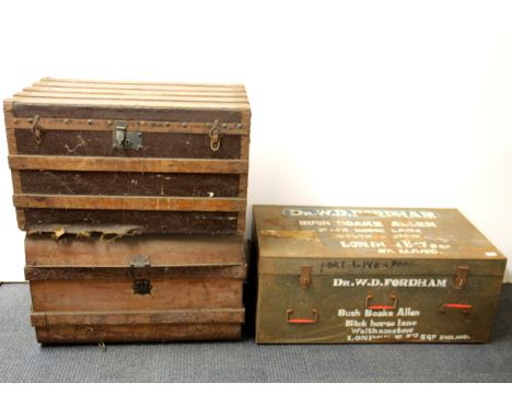 A large metal cabin trunk and two wooden and canvas cabin trunks.