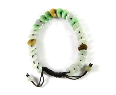 A pretty Chinese adjustable child's silk bracelet threaded with mixed colour jade coins for luck, bead Dia. 7mm.