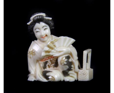 An early 20th century Japanese signed carved ivory netsuke of a geisha with a fan, H. 4.5cm.