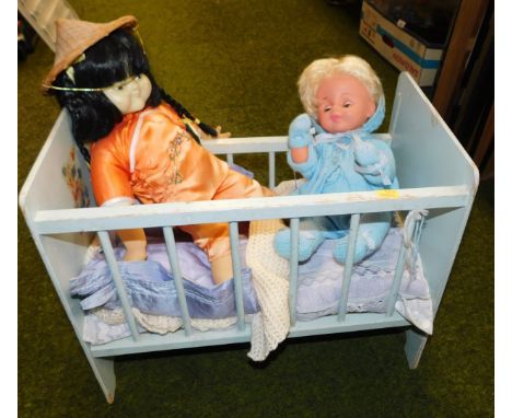 A child's play cot, including two dressed dolls, in traditional knitted outfits