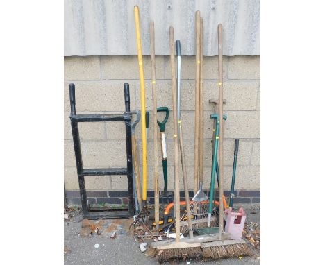 A quantity of garden tools, including hard brushes, leaf rake, secateurs, wood saw, garden fork, and a sack barrow.