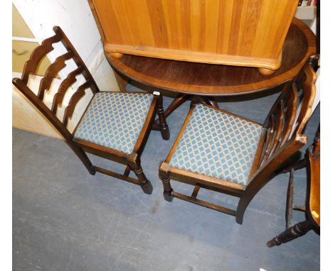 A pair of hardwood ladder back chairs, upholstered in a blue and gold fabric.