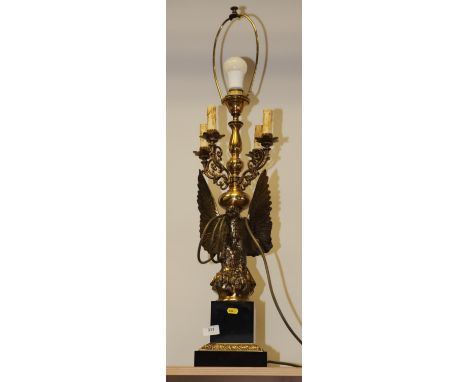 A brass table lamp, in the form of an eagle perched on a rock, with four scrolled arms, on a square marble base, 37" high ove