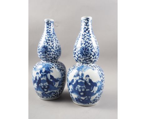 A pair of Chinese blue and white double gourd vases with panelled figure decoration on a flower and scroll patterned ground, 