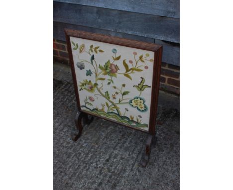 An early 20th century walnut framed firescreen with crewelwork panel end splay supports, 20" wide 