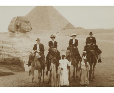 Late 19th century albumen photograph print depicting four figures atop camels posing in front of the Great Sphinx and the Gre