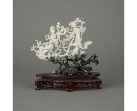 Elaborately carved Chinese jadeite sculpture depicting two women standing atop cresting waves. Well-formed from a black to wh