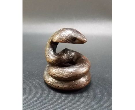 Japanese carved wood netsuke modelled as a coiled cobra with inset eyes, signed to the base.