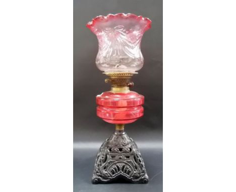 Victorian oil lamp with cranberry blush glass shade and cranberry reservoir over a cast iron base.