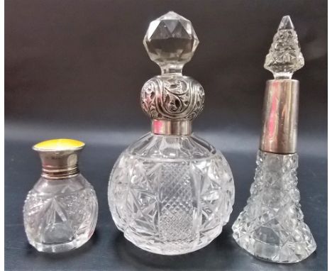 Three silver mounted cut glass scent bottles, one with guilloche yellow enamel screw lid, London 1923.