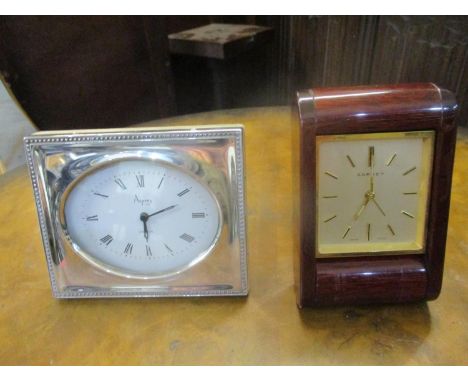 An Asprey silver clad dressing table clock, London 1985 and another Asprey dressing table clock having a wood effect case 