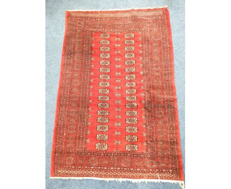 VINTAGE BOKHARA WOOLLEN RUGon red ground with cream medallions, 130 x 193cm with fringing
