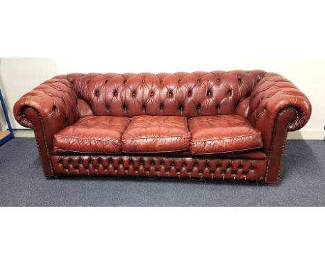 VINTAGE THREE SEATER LEATHER CHESTERFIELD SOFAof oxblood colour with button back detail, raised on castors, 198cm x 66cm x 89